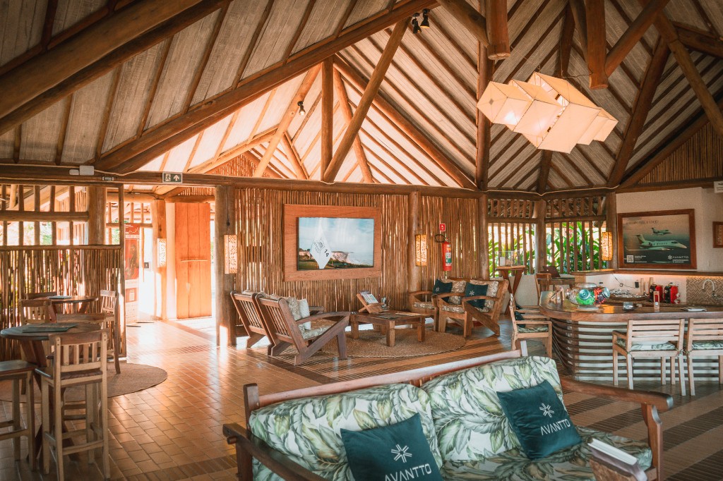 Interior do terminal: salão rústico de luxo com tecto em madeira, área de estar e bar.